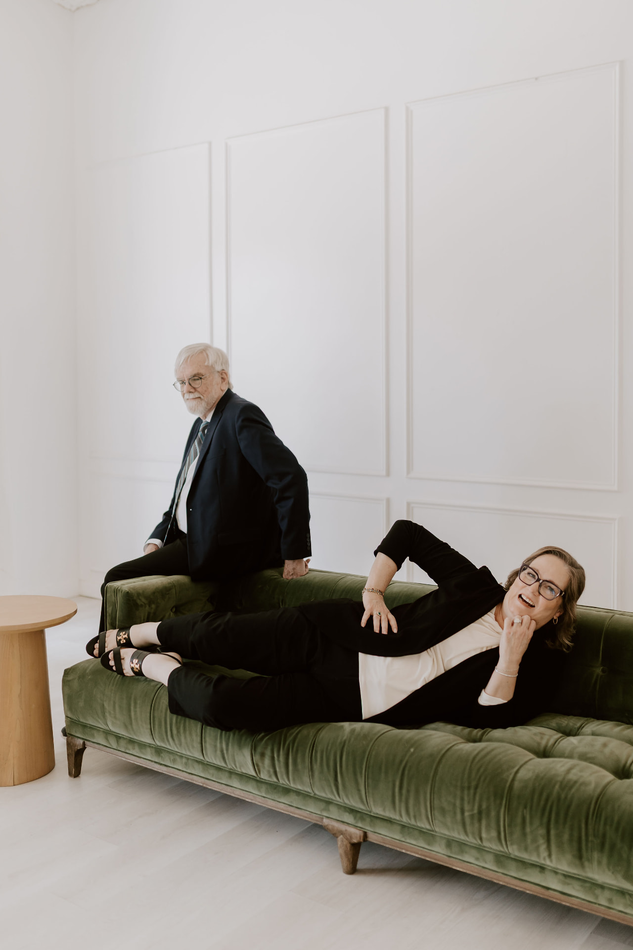 Two team members posing playfully on a green velvet sofa