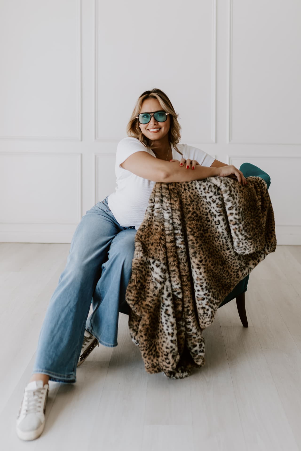 Team member seated in a teal armchair with a leopard-print throw