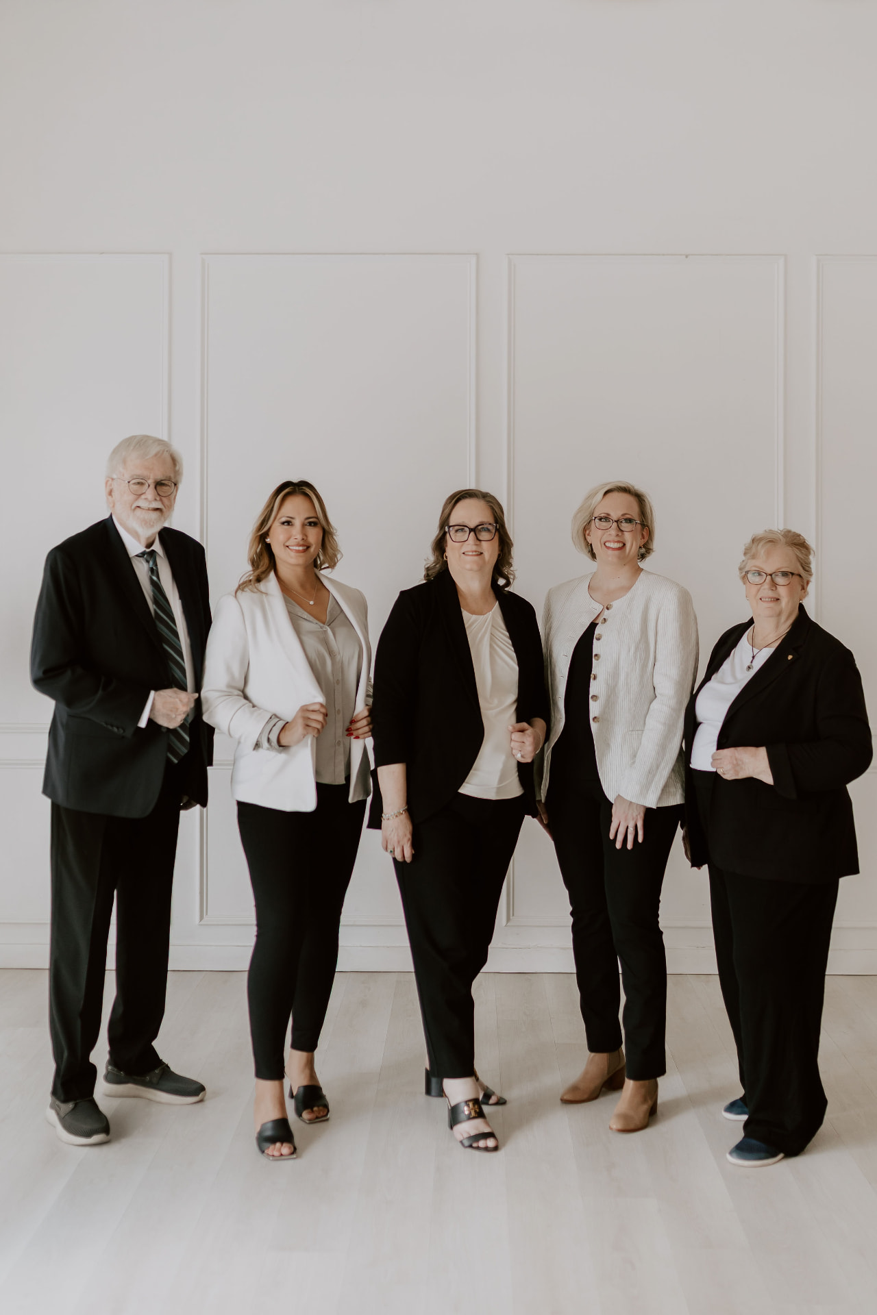 Five team members standing together in business attire